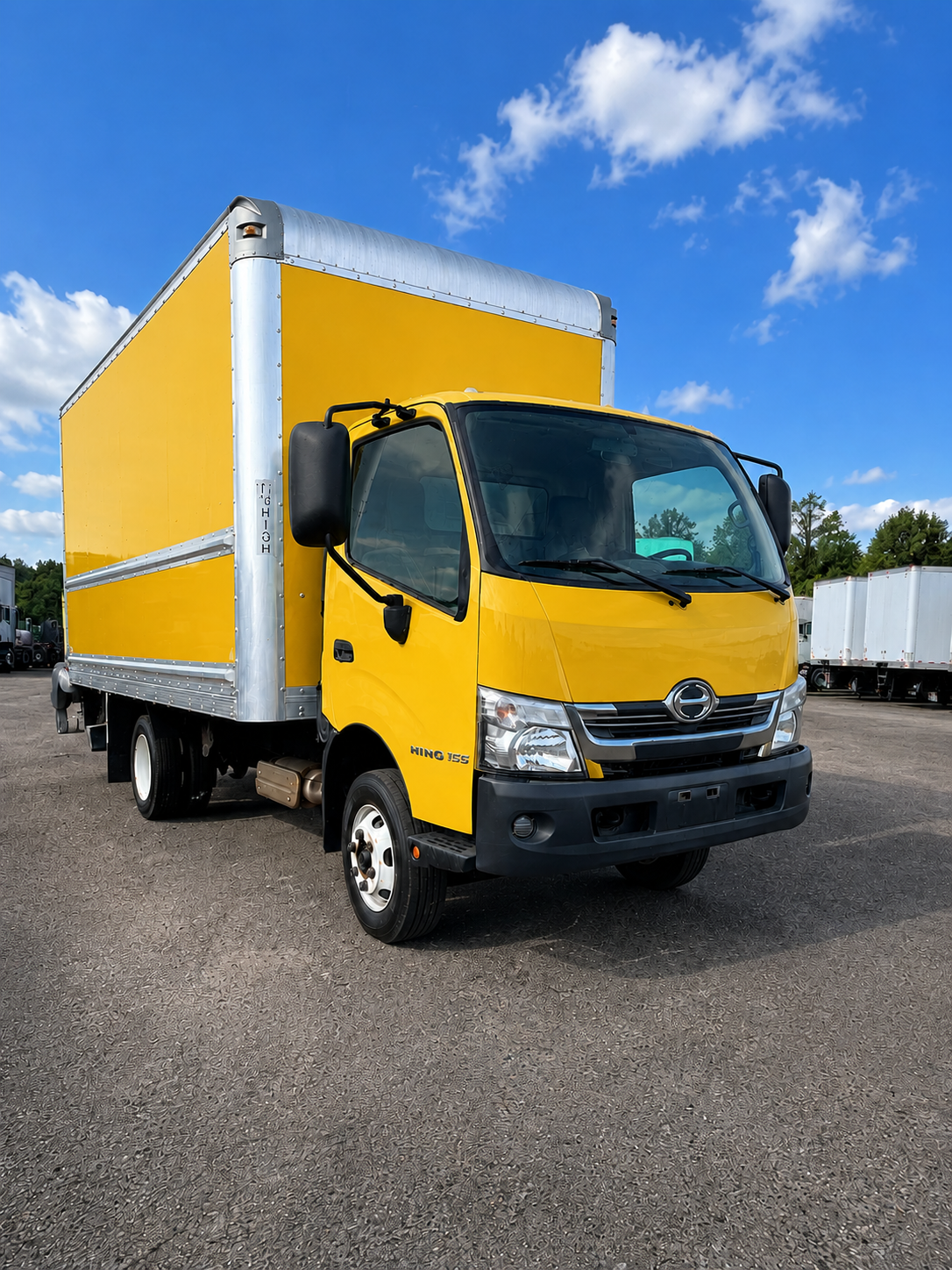 Yellow box truck parked under blue sky